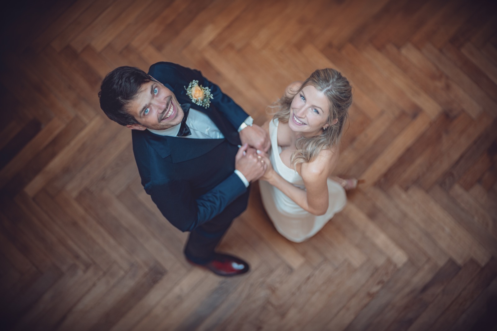 Brautpaar blickt nach oben – Perspektive von oben auf Parkett