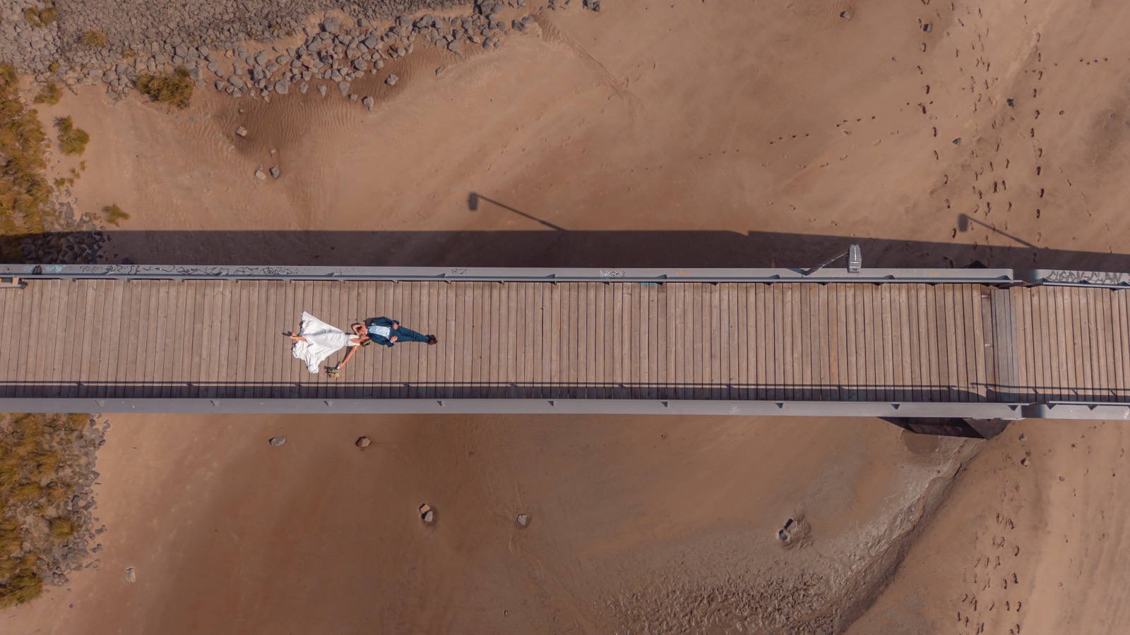 Drohnenaufnahme Brautpaar liegend auf Brücke am Strand