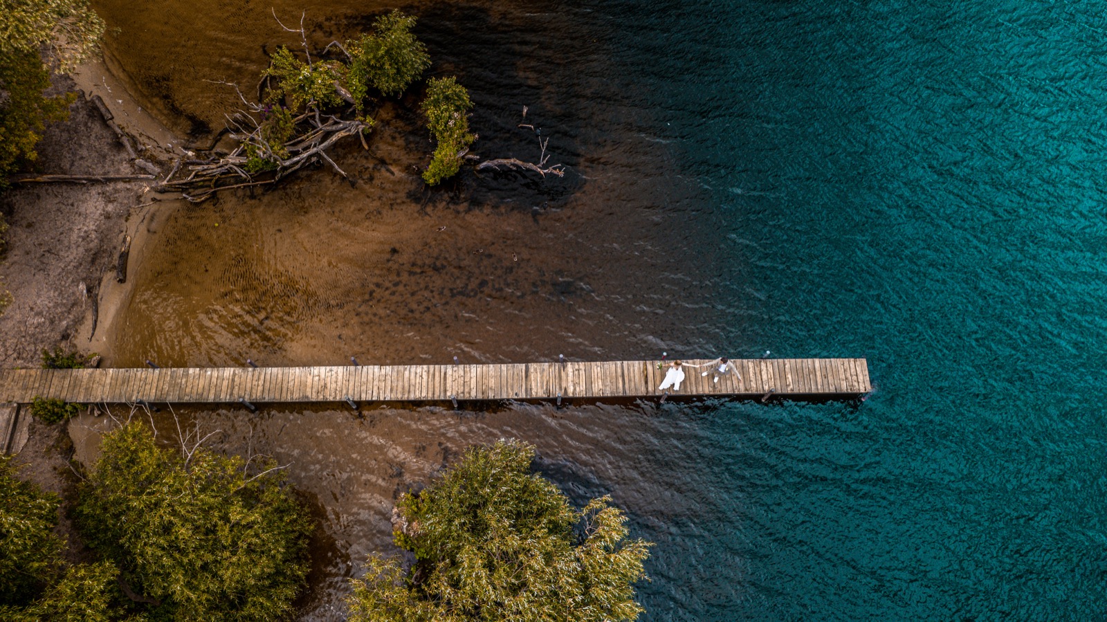 Drohnenaufnahme Brautpaar auf Steg – türkises Wasser